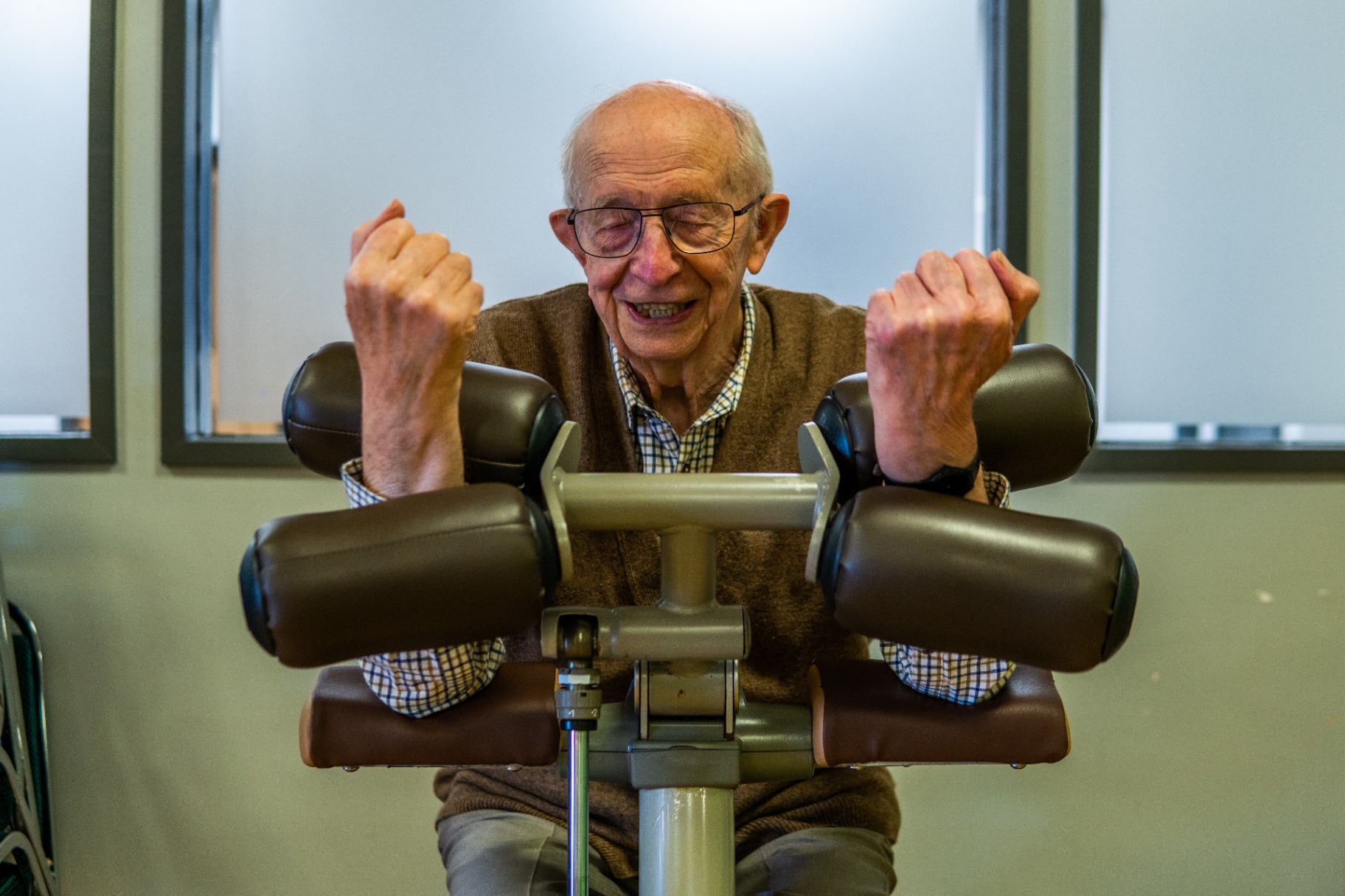 An older man exercising on a seated gym machine.