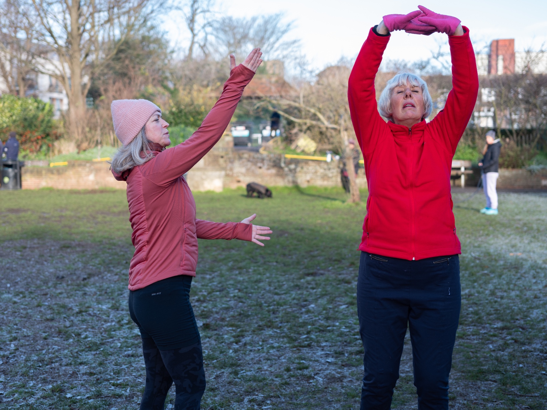 Two women stretching outdoors on a frosty morning.