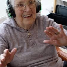 A care home resident smiling and dancing while wearing silent disco headphones
