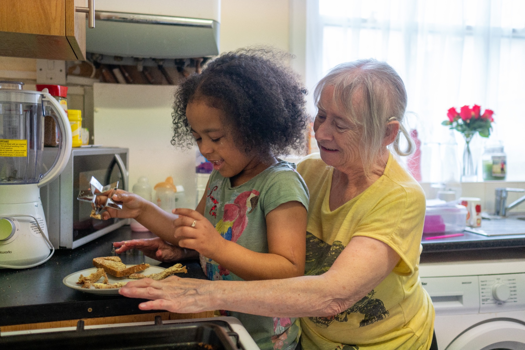 An older person at home in the kitchen with a grandchild, showing daily living and independence.